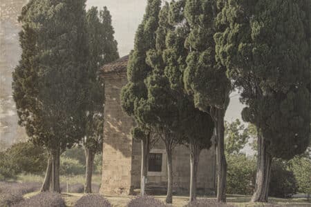 Fotografía de aspecto rústico en la que se ve el Oratorio de San Guido rodeado de cipreses y lavanda